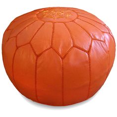 an orange leather poufle with intricate stitching on the outside and inside, sitting on a white surface