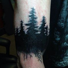 a man with a forest tattoo on his arm