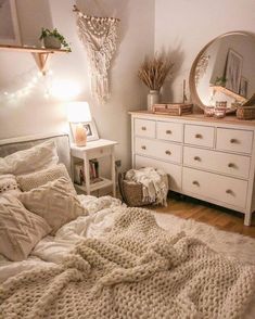 a bedroom with a white bed, dresser and mirror on the wall next to it