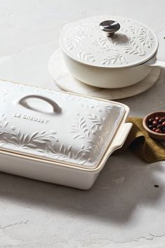 a white casserole dish sitting on top of a counter next to a brown bowl