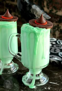 two mugs filled with green liquid and topped with chocolate on top, sitting next to each other