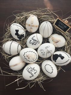 an arrangement of white eggs with black and gold designs on them in a nest filled with hay