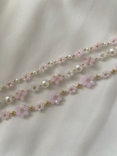 three strands of pearls and pink flowers on white fabric