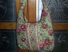 a green floral purse hanging on a wooden door