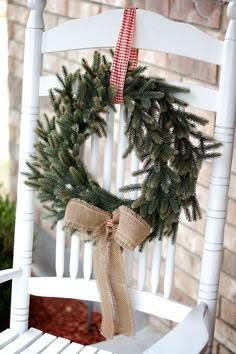 a white rocking chair with a wreath on the back and a burlap bow hanging from it