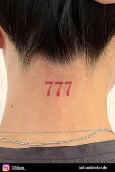 the back of a woman's neck has a small red number tattoo on it