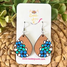 the wooden earrings are decorated with blue flowers