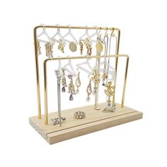 a gold jewelry rack with earrings and rings on it's display stand against a white background