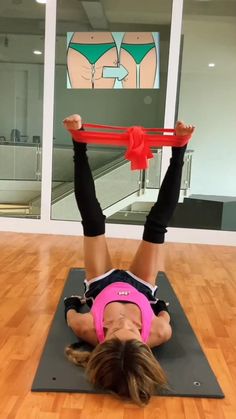 a woman is doing an exercise on a yoga mat with a red ribbon around her neck