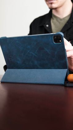 a man sitting at a table with an ipad in front of him and holding the case