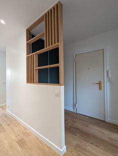 an empty room with white walls and wooden shelves on the wall, along with hardwood flooring