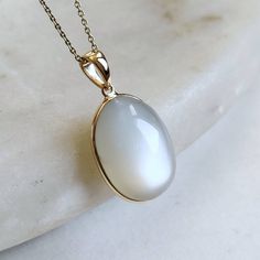 ITEM DESCRIPTION: >>The pendant is made from Solid 14K Yellow Gold. Gemstone used is absolutely natural and ethically sourced. >>Natural White Moonstones in bezel setting are studded on it with utmost precision. >>This is a minimalist design and is absolutely hassle-free and everyday jewelry. ✓ Gem: White Moonstone ✓ Gem size: 13x18 mm ✓ Gem weight: 15 carats ✓ Gold purity: 14K (58.33% approx.) ✓ Gold weight: 0.61 grams ✓ Gross weight: 3.61 grams The Gold purity is guaranteed and it comes with a White Gemstones Fine Jewelry As Gift, White Gemstones For Gifts, Fine Jewelry Style, White Gemstones For Gifts In Fine Jewelry Style, Elegant Moonstone Gemstones Gift, Elegant Moonstone Gemstones For Anniversary, Elegant White Jewelry With Large Stone, Elegant White Necklaces With Large Stone, White Chalcedony Jewelry For Anniversary, White Moonstone Classic Jewelry