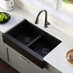 a kitchen sink with two black bowls on the counter