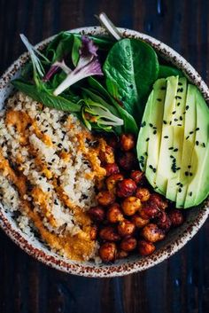 a bowl filled with rice, beans and avocado on top of a wooden table