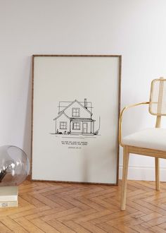 a framed drawing sitting on top of a wooden floor next to a chair and lamp