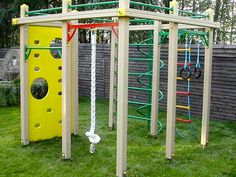 an outdoor play area with swings and climbing bars in the back yard, next to a wooden fence