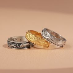 three different colored wedding rings sitting on top of each other in front of a beige background