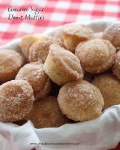 a bowl filled with sugar covered donuts on top of a red and white checkered table