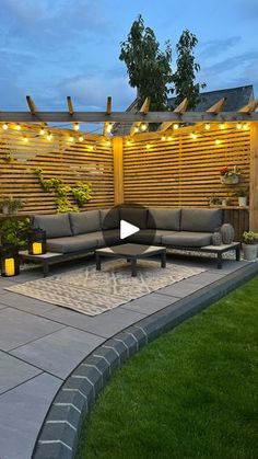 an outdoor patio with lights strung over the seating area, and grass in front of it