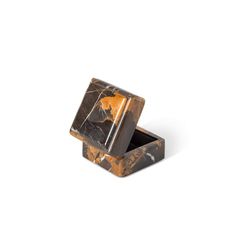 an orange and black marble ring in a box on top of a white surface with the lid open