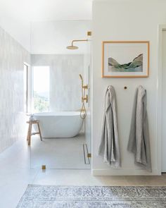 a bathroom with a bathtub, rug and two towels hanging on the wall next to it