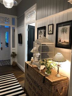 a birdcage sitting on top of a wooden chest in a living room next to a door