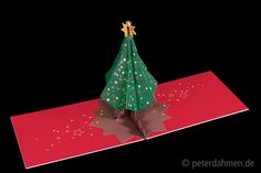 an origami christmas tree on top of a red paper with gold stars and confetti