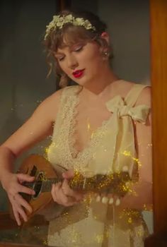 a woman wearing a white dress and holding a guitar in front of a mirror with lights on it