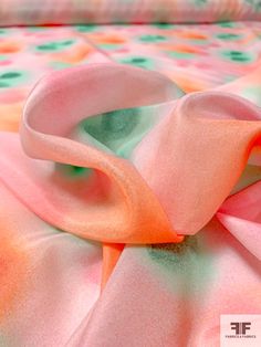 a pink and orange blanket on top of a bed with polka dot print sheets in the background