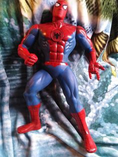 a close up of a spider man figure on a bed sheet with fish in the background