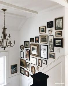 a staircase with many pictures on the wall and a chandelier hanging from the ceiling