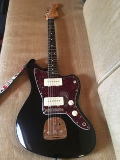 a black electric guitar sitting on top of a couch