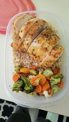 a plastic container filled with rice, meat and veggies on top of a table