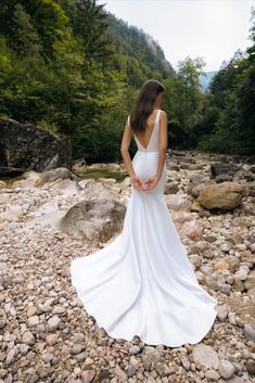 a woman in a white dress standing on rocks