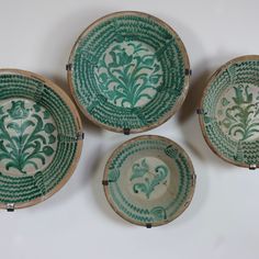 four green and white bowls with designs on them