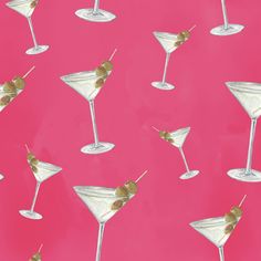 several martini glasses with olives on a pink background