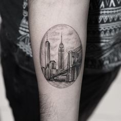 a black and white photo of a cityscape in a circle tattoo on the arm