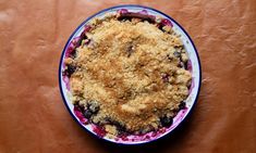 a blue and white dish with crumbled topping on the top sits on a brown surface