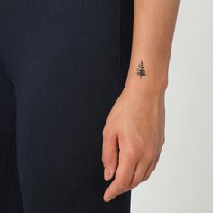 a person with a small pine tattoo on their left arm and the other hand behind her