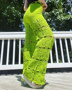 a woman standing on a deck wearing bright green pants with holes in the front and side