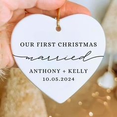 someone holding up a heart shaped ornament with the words our first christmas married