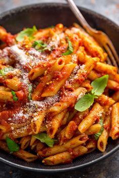 a bowl filled with pasta covered in sauce and parmesan cheese