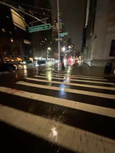 a city street at night with cars and people crossing the street in the crosswalk