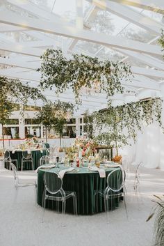 a table set up for an event with green linens and clear chairs