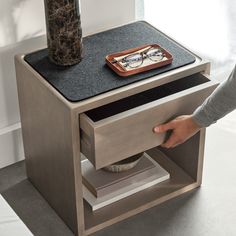 a person is opening the drawer on a side table with a bowl and glasses in it