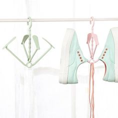 two pairs of shoes hanging on a clothes line next to a window with curtains in the background