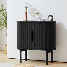 a black cabinet sitting on top of a hard wood floor next to a white wall