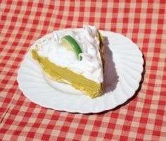 a piece of pie sitting on top of a white plate covered in whipped cream and lime