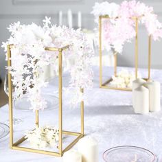 some white and pink flowers are in vases on a table with other items around it