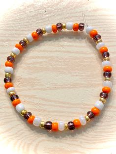 an orange, white and gold beaded bracelet on a wooden surface with beads in the middle